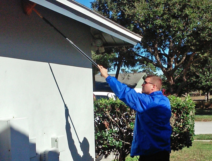 pest control technician spraying exterior of house